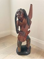 Front view of the wooden reggae sculpture showing detailed carvings and paintwork.