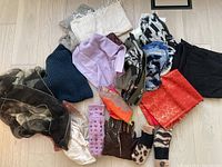 Overview of assorted scarves, gloves, mittens, and winter mufflers laid out on a floor.