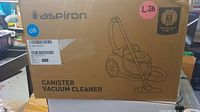 Closed cardboard box of Aspiron canister vacuum cleaner with brand name, model, and labels