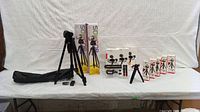 Full lot overview showing multiple tripods, flexible pod holders and several boxed Mobifoto mini tripods and pods displayed on a white table.