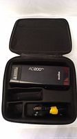 Godox AD200 Pro flash unit in open black carrying case with accessory cable.