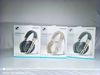 Front of three boxed headphones; two black units flanking one beige unit