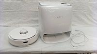 Front view of robot vacuum and docking station side by side on white background