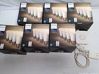 Six sealed Philips Hue White A19 bulb boxes alongside Hue Bridge and cables