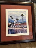 Framed color seriolithograph showing a waterfront scene with buildings, palm trees, water reflections, signed by artist.