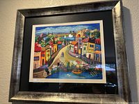 Framed colorful village scene serigraph signed by the artist.