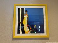 Framed signed limited edition print by Emile Bellet titled 'Instant Bleu II' showing a woman in yellow dress with floral accents.