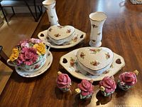 Full view of the floral porcelain set including vases, heart-shaped candy bowls, centerpiece, and salt and pepper shakers on table