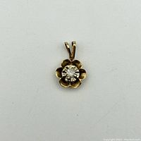 Front view of the 10k gold flower-shaped pendant with central diamond.