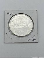 Reverse side of the 1963 Canadian silver dollar coin depicting two figures paddling a canoe with the year 1963 and 'CANADA DOLLAR' text.