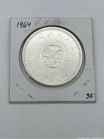 Reverse of 1964 Canadian silver dollar coin showing floral emblem with inscriptions.