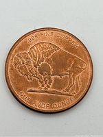 Obverse side of copper coin showing buffalo design with purity and weight inscriptions.