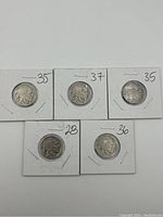 Five Buffalo nickel coins in white cardboard holders, showing dates 1928, 1935 (two coins), 1936, and 1937.