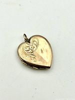 Photo of the heart-shaped 9ct gold locket front side showing engraved decorative patterns.
