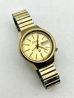 Front view of gold-tone Bulova Accutron wristwatch showing dial with day and date display and slight wear.