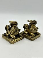 Front angled view showing the detailed brass Foo dog statues with red eyes and decorative square bases with engraved characters.