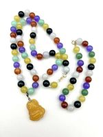 Full view showing the necklace with yellow jade Buddha pendant and matching multi-color jade bead bracelet laid out separately