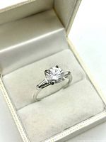 Sterling silver ring in a padded box showing the large round clear cubic zirconia and baguette-cut accents.