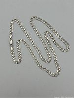 Full view of the sterling silver curb link chain necklace laid out on flat surface showing length and overall design.
