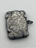 Front view of the sterling silver match vesta showing floral engraving and scalloped edges