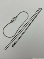 Sterling silver necklace and bracelet laid out flat showing full length and clasp types.