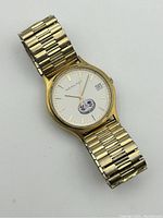 Front view of watch face showing dial, hands, date window and emblem