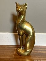 Front view of the vintage large brass cat figurine, showing polished golden brass and detailed face.