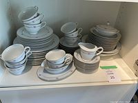 Wide shot of the Wyndham Tudor china dinnerware set showing cups, plates, bowls, cream and sugar set, gravy boat, and trays arranged in cabinet.