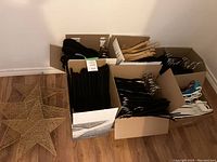 Overview of all boxes showing wooden, plastic, fabric-covered hangers, and wire star decorations on floor