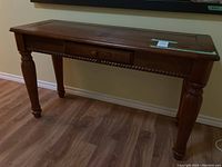 Full view of wooden console table with wear on top surface, showing front and legs