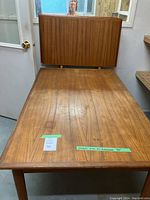 Full view showing table with both extension leaves propped upright behind.