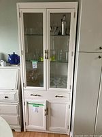 Full-frontal view of the assembled display cabinet showing glass doors, central drawer, lower doors