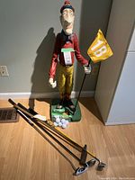 Full shot of statue on floor with golf clubs and balls arranged around base