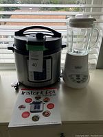 Photo of Insignia Instant Pot and Cuisinart blender side by side with Instant Pot Miracle recipe book in foreground