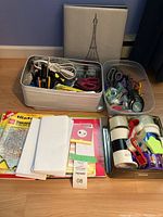 Wide view showing all items in the lot including three containers with scissors, tape, and pens, a photo album, and writing pads.