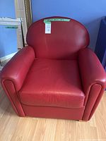 Front view of red leather chair showing seat cushion, arms and curved back