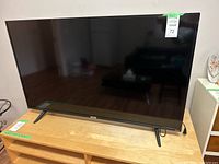 Front view of 50-inch TCL Roku TV on wooden bench with two V-shaped legs