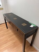 Black Asian-themed console table with three drawers shown at angle, highlighting the wood finish and drawer configuration.