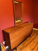Teak veneer six-drawer dresser with matching mirror in background