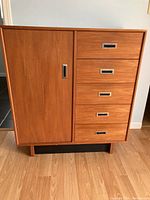 Front view of teak tallboy dresser showing left cupboard door and five drawers on right