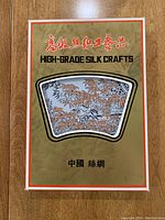 Box packaging showing the silk tablecloth labeled as High-Grade Silk Crafts with Chinese text and viewing window revealing part of the design inside.