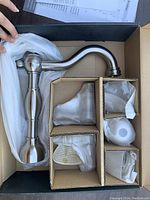 Photo showing boxed faucet body and plumbing components wrapped in protective fabric.