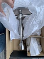 Top view of tall brushed nickel faucet body inside the packaging with protective white wrapping partially removed