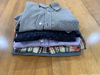 Stack of four men's button-down shirts showing different colors and patterns