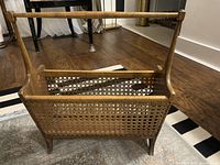 Front and side view of mid-century modern cane rattan and wood magazine rack with wooden handle and woven cane sides.