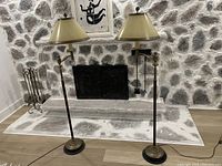 Photo showing both vintage brass swing-arm floor lamps with paper shades set in front of a stone fireplace.