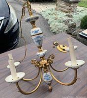 Full view of the 5-branch vintage chandelier showing the ceramic and brass components, the blue floral decoration on white ceramic, and candle-style light holders.