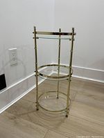 Full view of vintage three-tier glass and metal table showing all shelves and metal frame with minor tarnish.