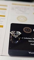 Loose round brilliant stone resting on GRA warranty card showing facets and sparkle