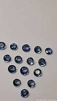 Multiple oval to round cut loose cornflower blue sapphires shown front and angled under light to display color and clarity.